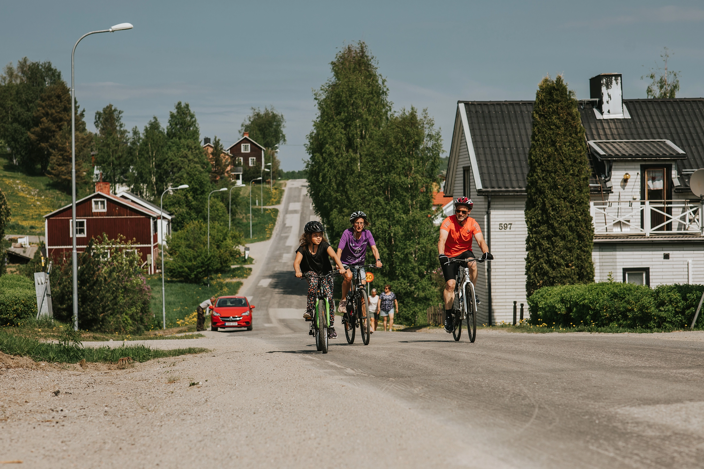 Tre stycken cyklande personer i ett samhälle