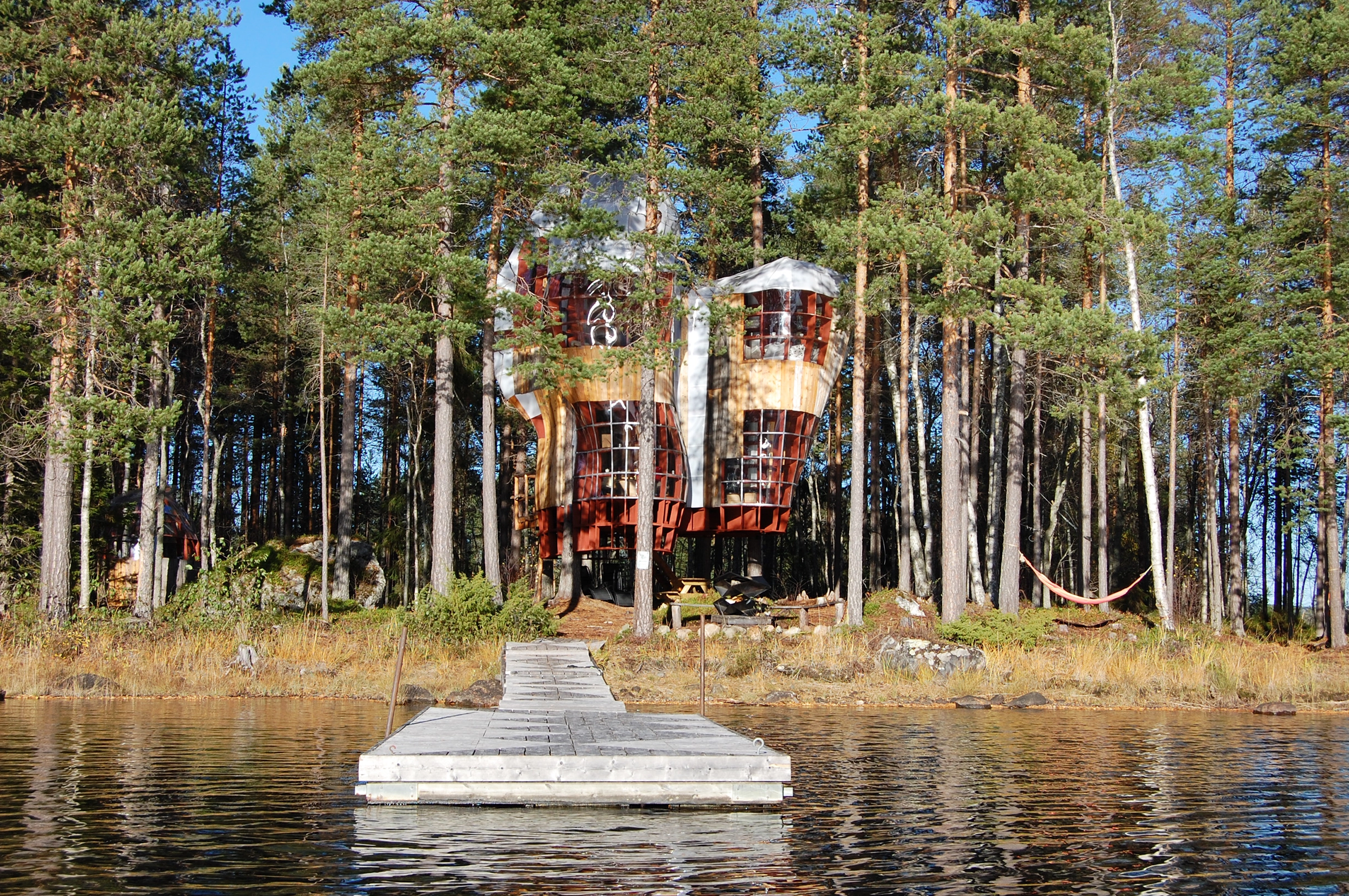 Ett hus i trädkronorna med en egen brygga till vattnet